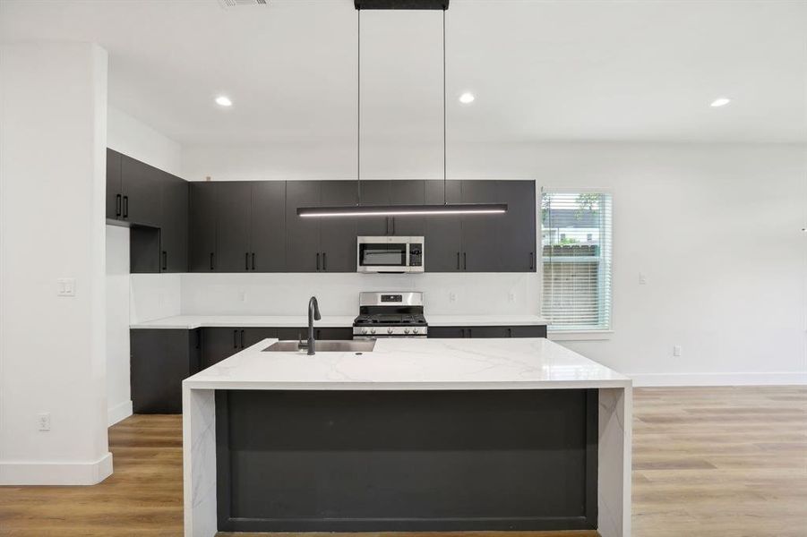 Sophisticated and streamlined design in kitchen with waterfall quartz countertop