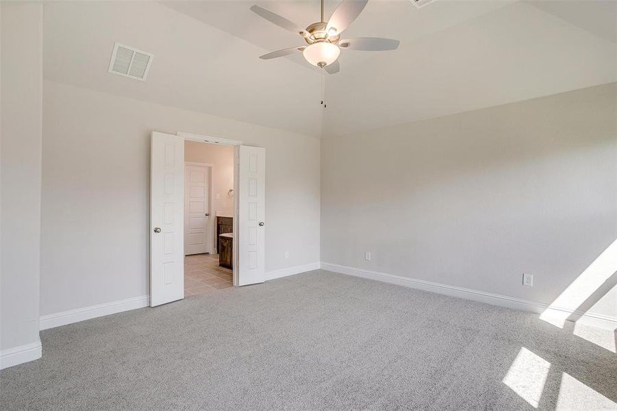 Unfurnished bedroom with lofted ceiling, light carpet, and ceiling fan