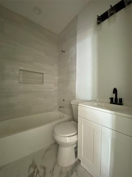 Full bathroom with tile patterned flooring, toilet, tiled shower / bath combo, and vanity