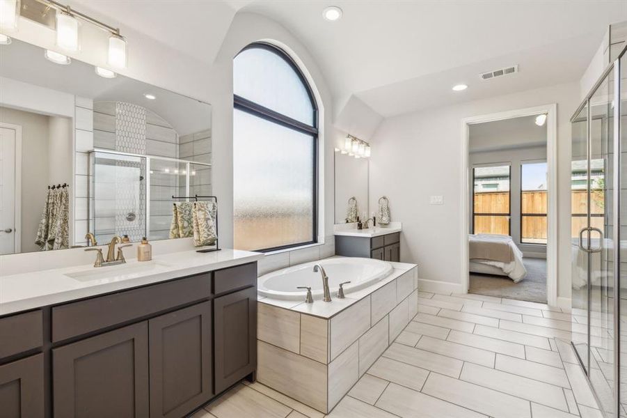 Bathroom featuring independent shower and bath, lofted ceiling, vanity, and tile patterned floors