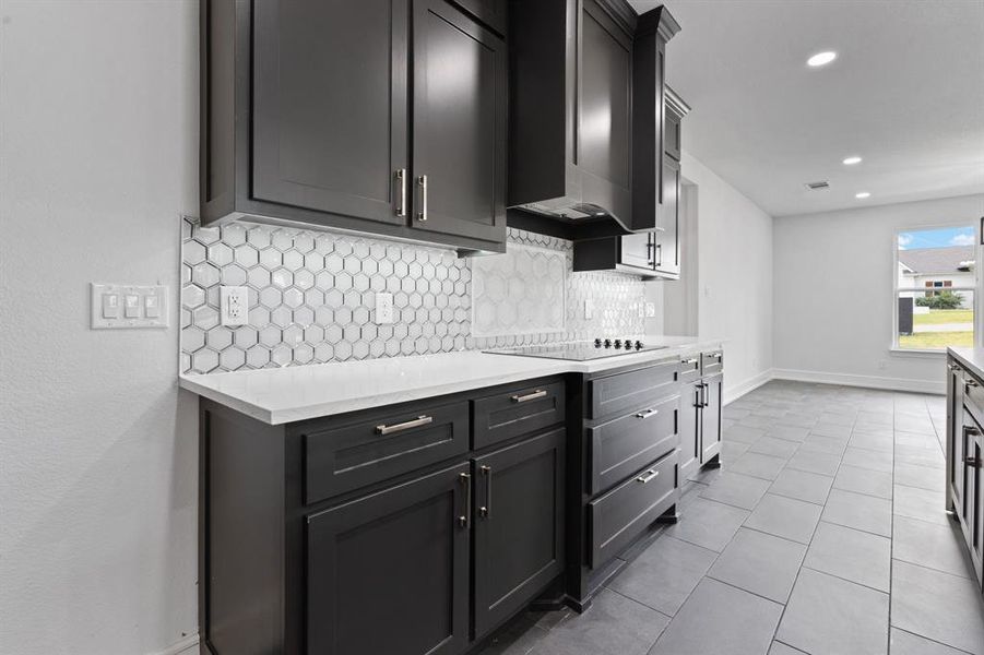Kitchen featuring light tile patterned flooring, tasteful backsplash, and black electric cooktop