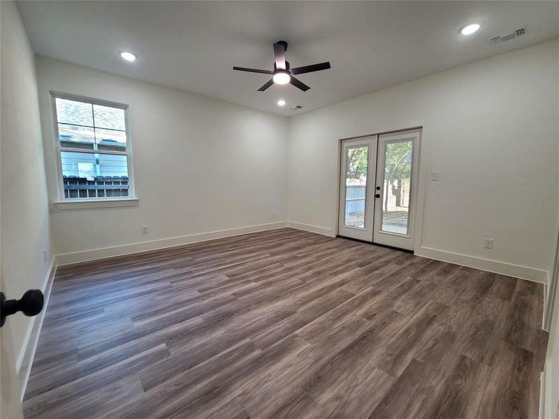 Empty room featuring dark wood-type flooring, ceiling fan, and french doors