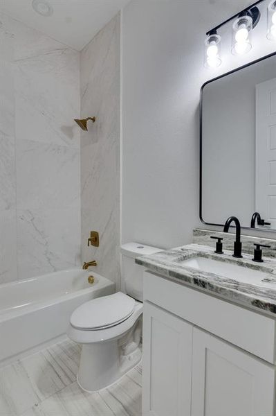 Full bathroom with vanity, tile patterned flooring, tiled shower / bath combo, and toilet