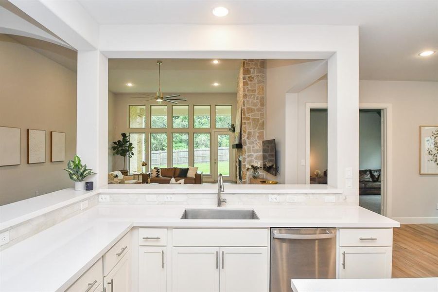 Modern kitchen featuring white cabinetry, stainless steel appliances, a gas cooktop, and a contrasting island with white countertop. The room has recessed lighting and tile floors.