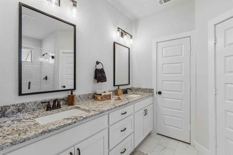 Bathroom featuring dual vanity, a shower, and tile patterned floors