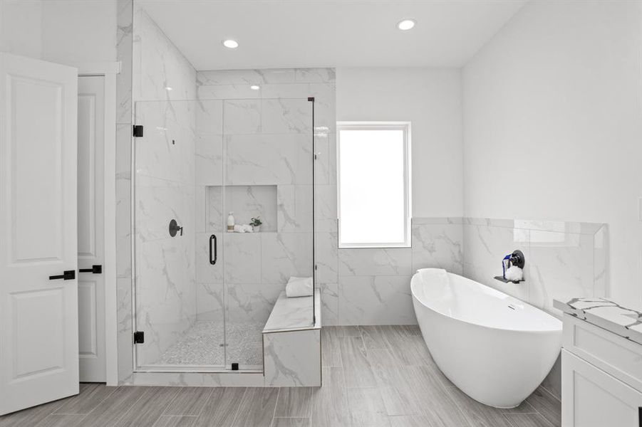 This en- suite features a porcelain garden soaking tub and custom walk-in frameless shower with bench, accented with matte black hardware.