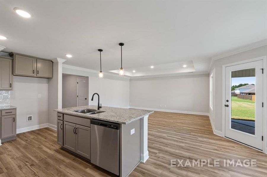 Kitchen with light wood-type flooring, gray cabinets, sink, hanging light fixtures, and stainless steel dishwasher