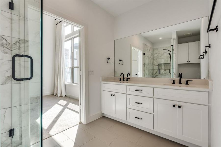 Bathroom featuring Double Sinks and Shower with Added Glass Shower Door