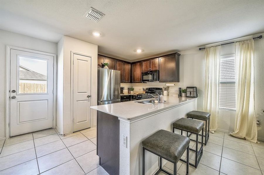 Kitchen featuring kitchen peninsula, a wealth of natural light, a breakfast bar, and black appliances