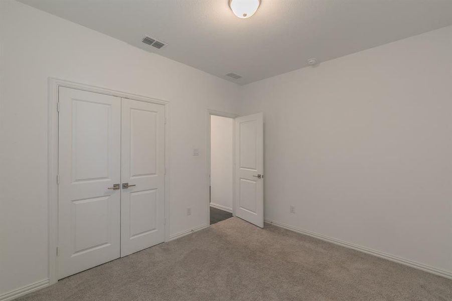 Unfurnished bedroom with light colored carpet and a closet