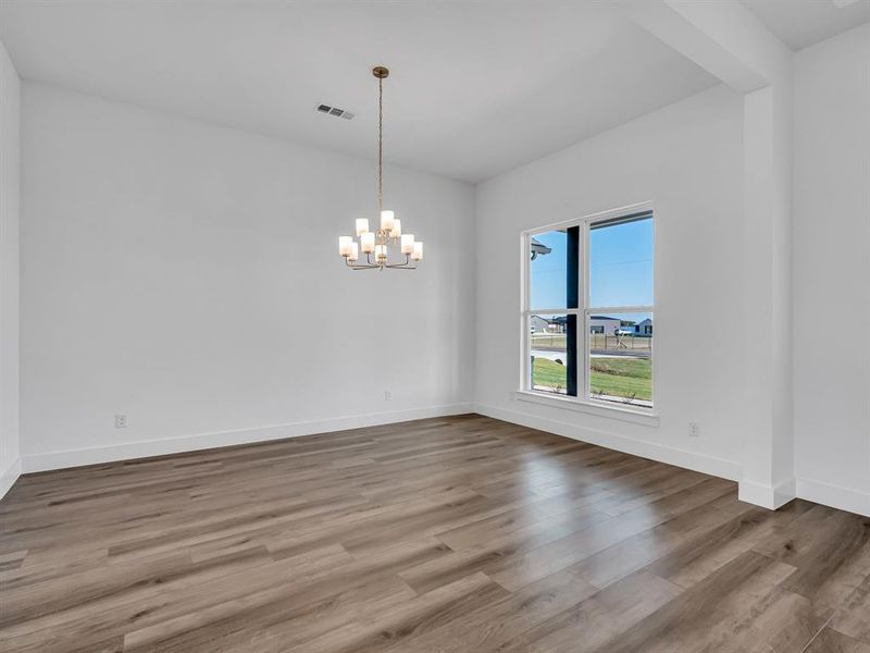 Spare room featuring a notable chandelier and hardwood / wood-style floors