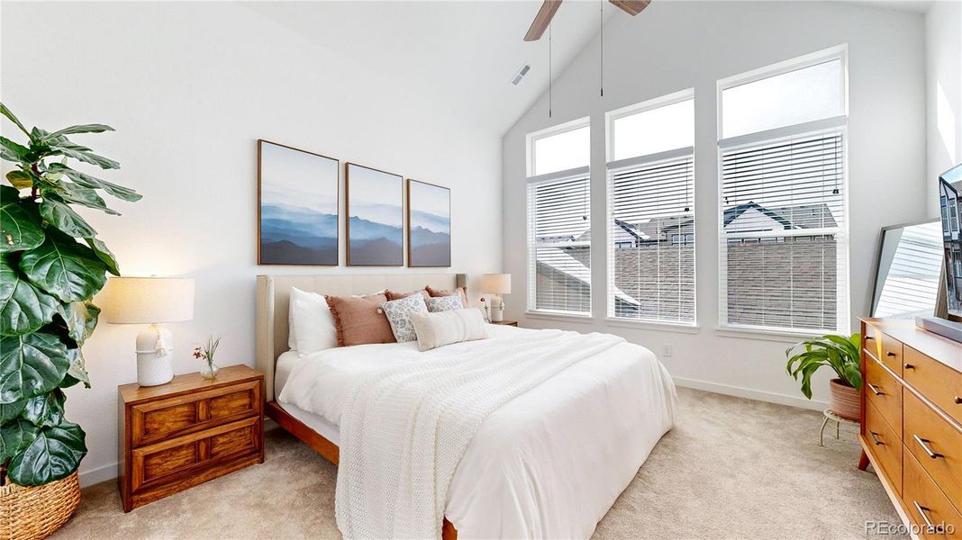 Grand primary bedroom with large picture windows and vaulted ceilings.