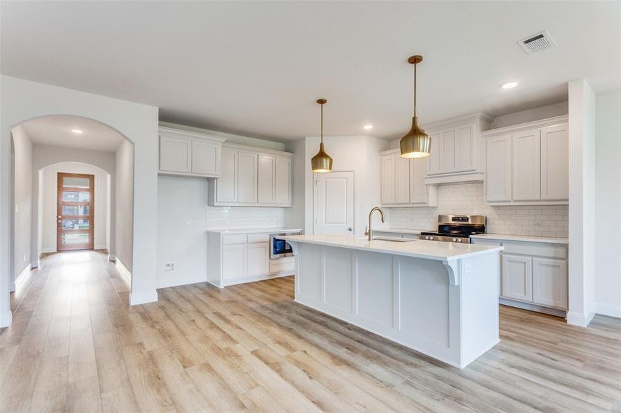 Kitchen featuring white cabinetry, sink, appliances with stainless steel finishes, and light wood-type flooring