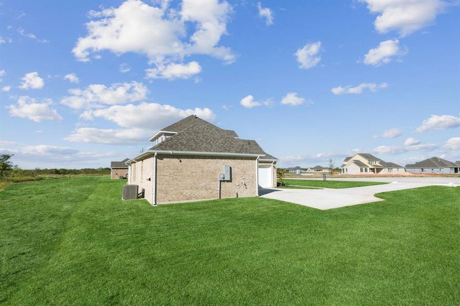 View of side of home featuring a yard, a patio, and central AC unit