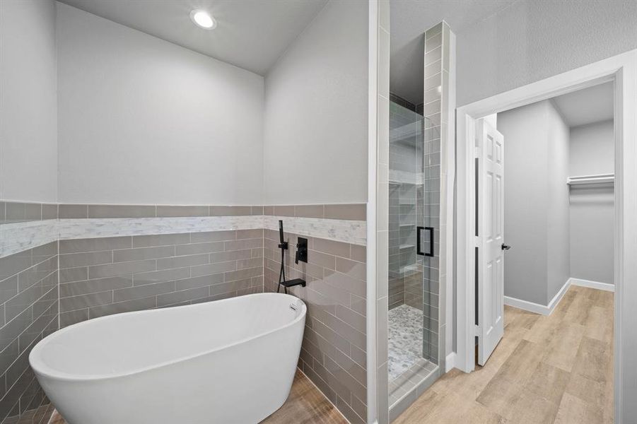 Bathroom featuring plus walk in shower, wood-type flooring, and tile walls