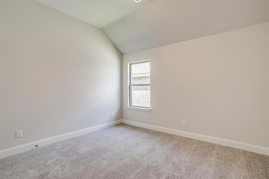 Spare room featuring lofted ceiling and light colored carpet