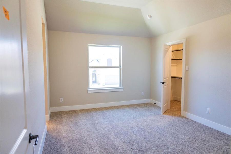 Carpeted spare room with vaulted ceiling