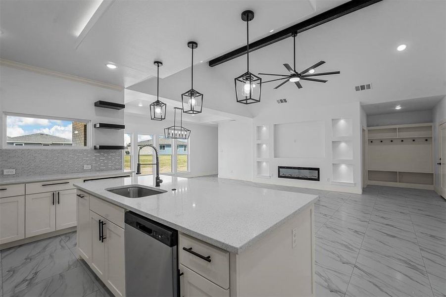 Kitchen with dishwasher, ceiling fan with notable chandelier, white cabinetry, hanging light fixtures, and a center island with sink