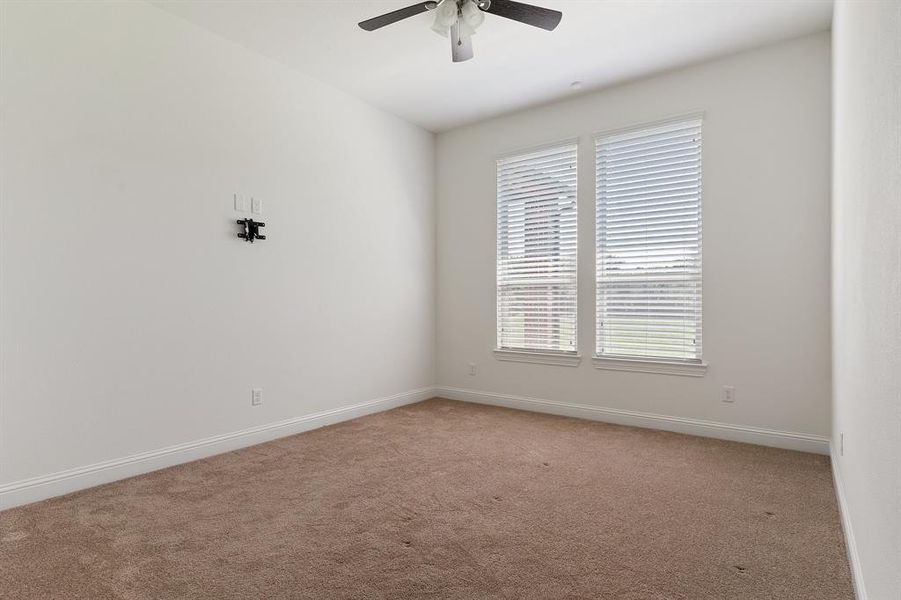 Spare room featuring a healthy amount of sunlight, light carpet, and ceiling fan