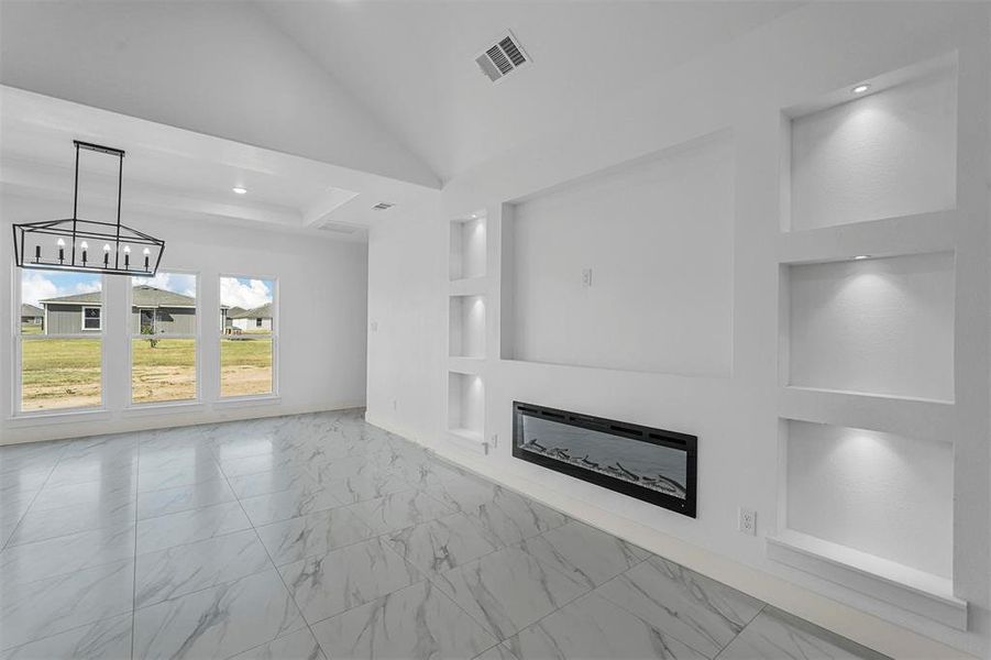 Unfurnished living room featuring a chandelier, built in features, and high vaulted ceiling