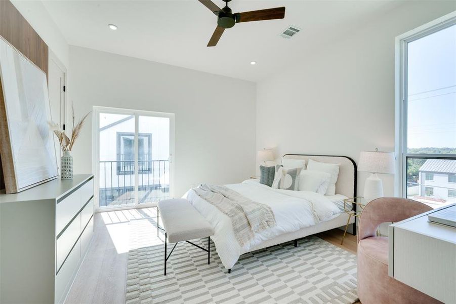 Bedroom featuring light hardwood / wood-style flooring, access to exterior, multiple windows, and ceiling fan