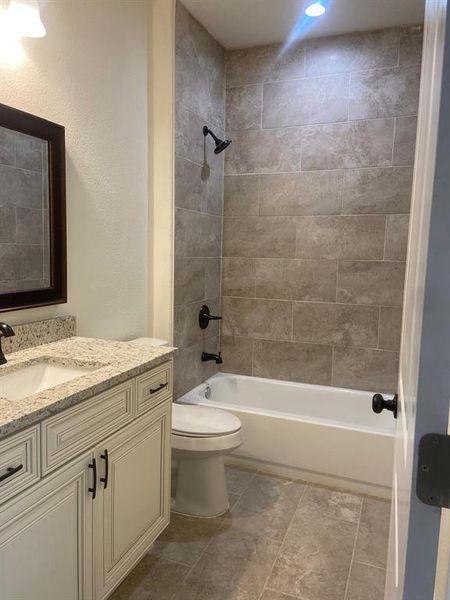 Full bathroom featuring tiled shower / bath combo, vanity, toilet, and tile flooring