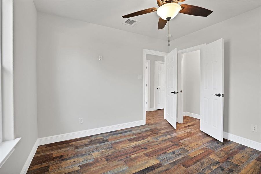 Unfurnished room with dark wood-type flooring and ceiling fan