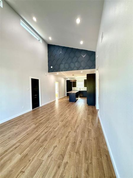 Unfurnished living room featuring light hardwood / wood-style floors and high vaulted ceiling