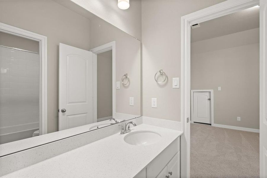 The secondary bath features tile flooring, white cabinetry and light countertops and a shower/tub combo. Perfect for accommodating any visiting family and friends.