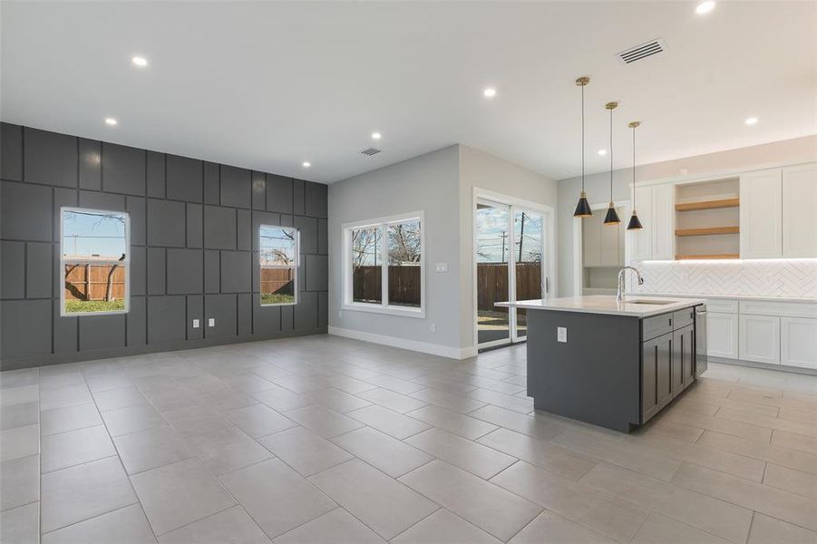 Kitchen with pendant lighting, light tile patterned flooring, an island with sink, white cabinetry, and decorative backsplash