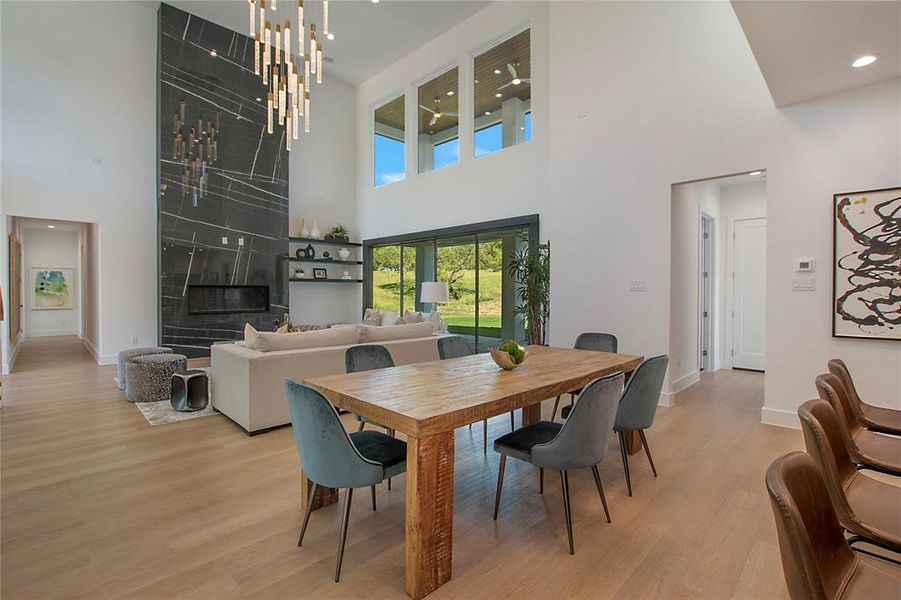 Dining space with a notable chandelier, a towering ceiling, and light hardwood / wood-style floors