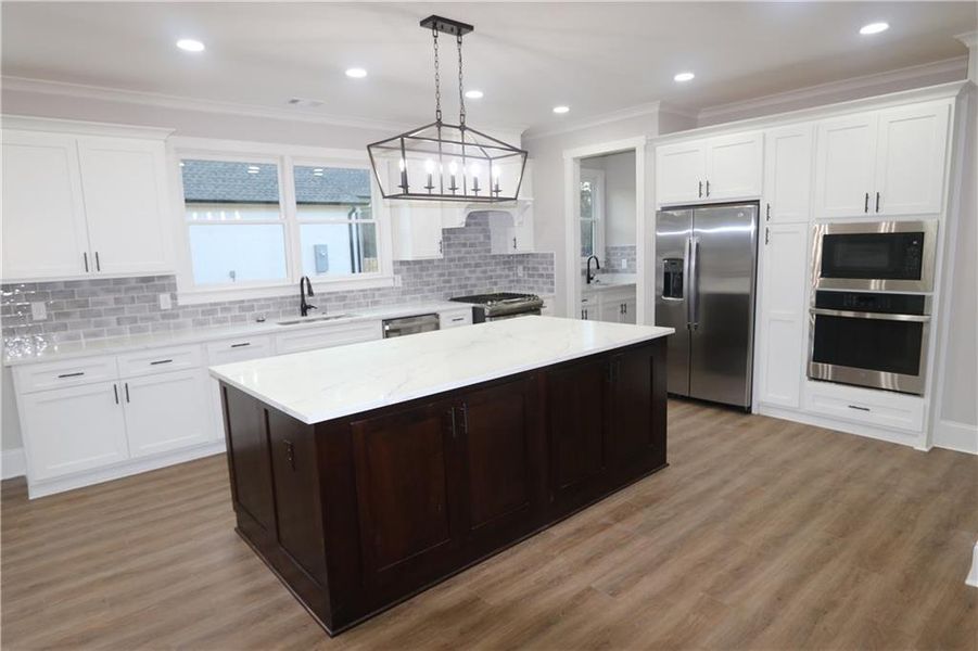 Kitchen featuring light wood-type flooring, appliances with stainless steel finishes, and a chandelier