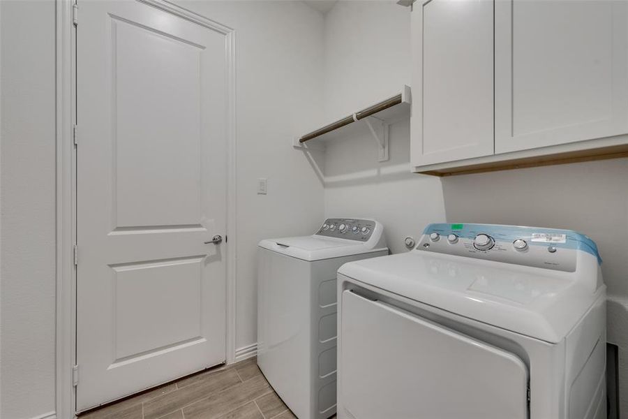 Laundry room with washer and dryer, cabinets, and light hardwood / wood-style flooring