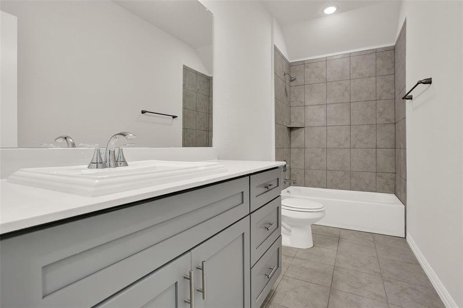 Full bathroom with tile flooring, tiled shower / bath combo, vanity, and toilet