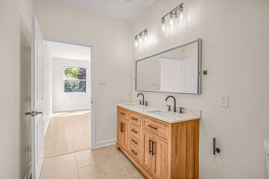 Primary bath with double sinks and stained wood vanity.