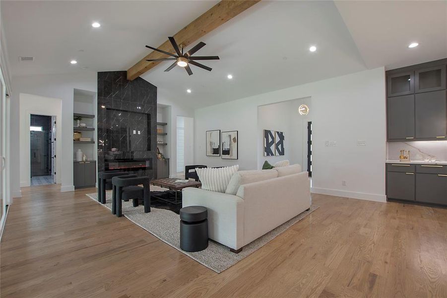 Living room with light hardwood / wood-style flooring, beam ceiling, ceiling fan, and high vaulted ceiling