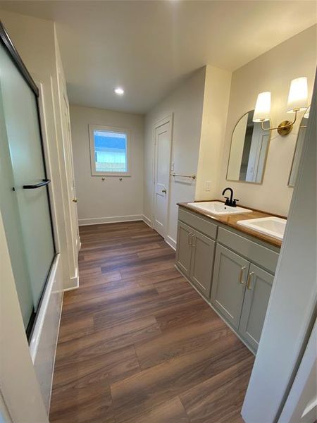 Bathroom with hardwood / wood-style floors, shower / bath combination with glass door, and vanity