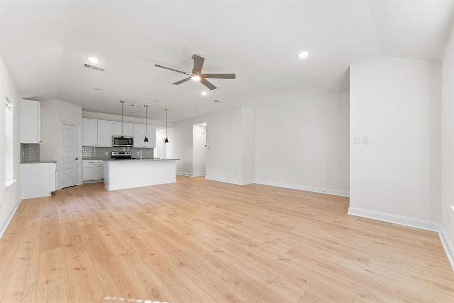 Unfurnished living room featuring light hardwood / wood-style flooring, lofted ceiling, and ceiling fan