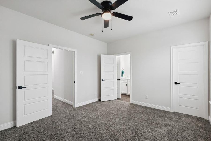 Unfurnished bedroom with carpet, ceiling fan, and ensuite bathroom