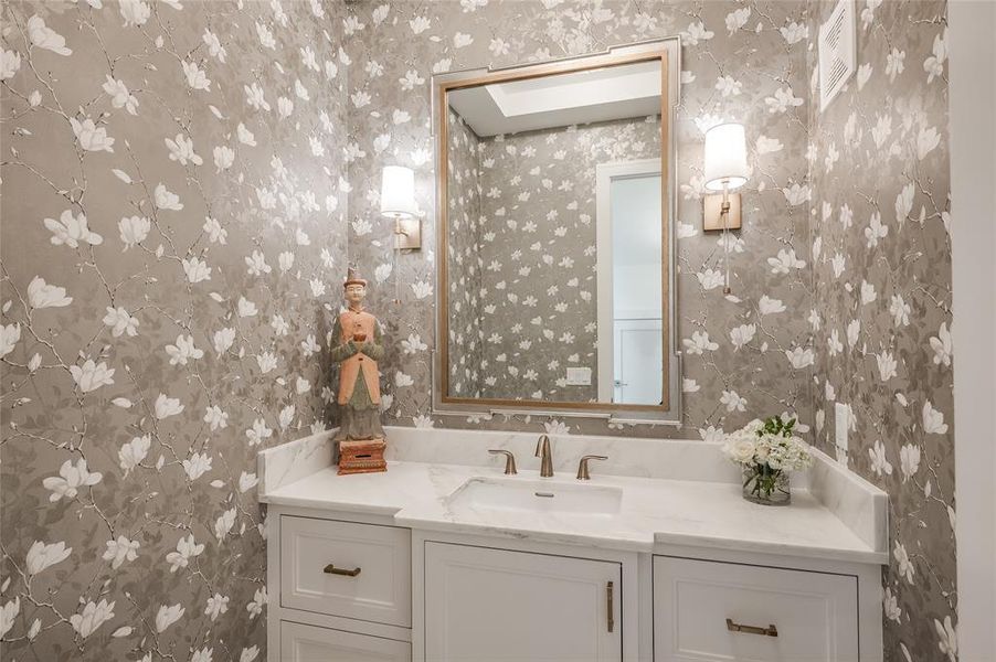 The elegantly appointed powder room, with custom designer wallpaper and marble countertops, is conveniently located off the entry.