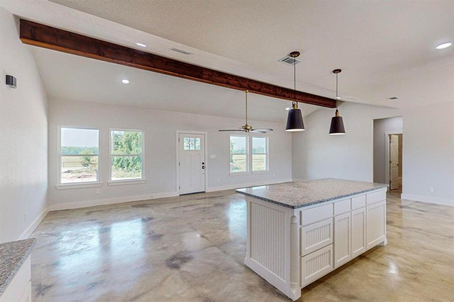 Kitchen with vaulted ceiling with beams, ceiling fan, white cabinetry, and hanging light fixtures