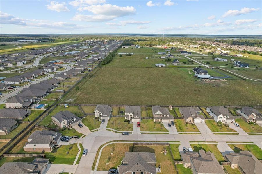 Aerial shot capturing the peaceful surroundings and the agricultural land behind the home, offering serene views with no backyard neighbors.