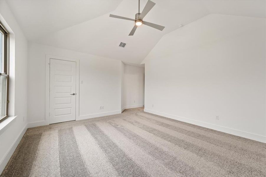 Unfurnished bedroom with light carpet, lofted ceiling, and ceiling fan