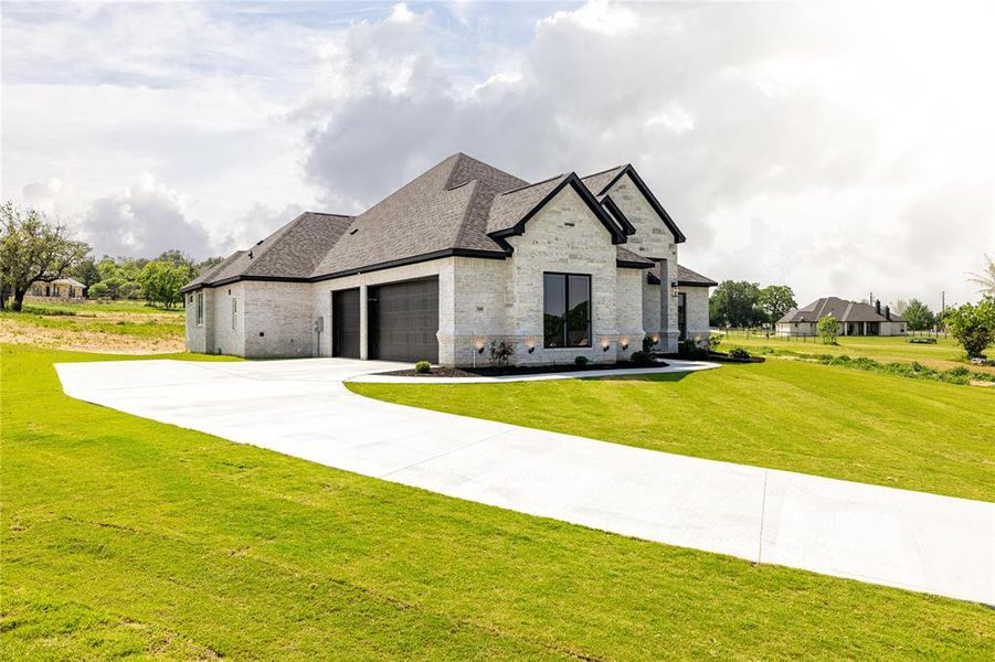 French country inspired facade with a garage and a front yard