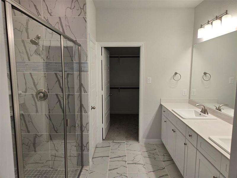 Bathroom featuring a shower with door and vanity