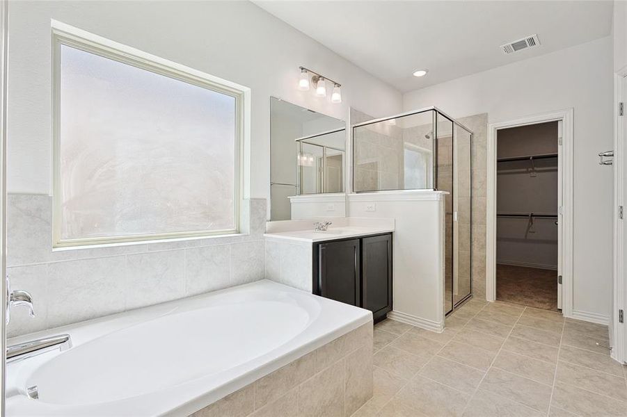 Bathroom with shower with separate bathtub, tile patterned floors, a wealth of natural light, and vanity