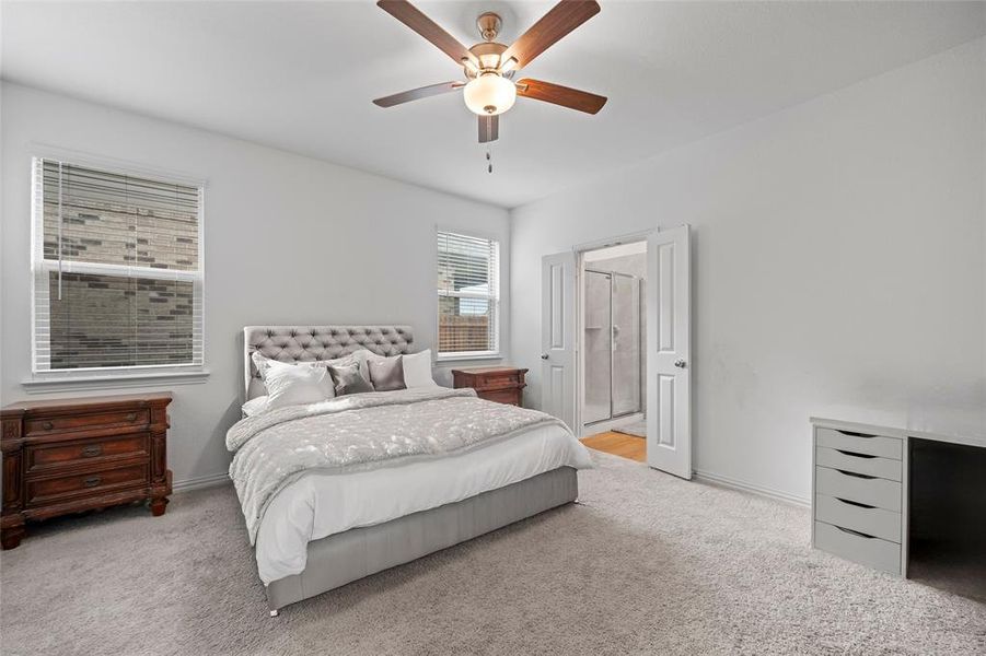 Bedroom featuring ceiling fan, ensuite bath, and light colored carpet