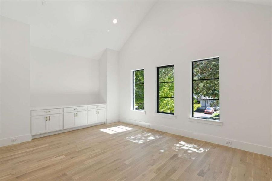 Spare room featuring light wood-type flooring and high vaulted ceiling