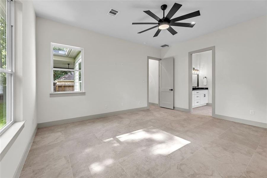 Master suite with tile flooring and lots of windows that is attached to ensuite bathroom