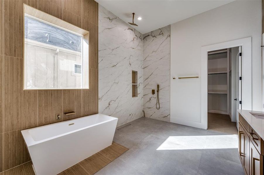 Bathroom featuring vanity, separate shower and tub, and tile walls